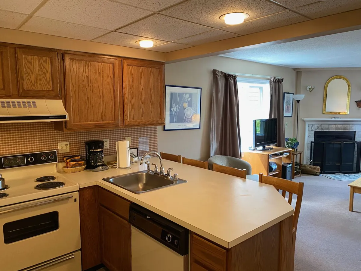 This image captures the open-plan living area with a view of the kitchen counter, sink, stove, and a glimpse into the main living space. The entryway can be inferred as just out of the frame, suggesting a direct transition from outside to the central hub of the condo, aligning with the section's emphasis on effortless arrival and convenience.